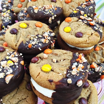COOKIES MENU: Pictured are our Peanut Butter Cookie Sandwiches. Two peanut butter cookies with Reese's Pieces dotted across the surface, sandwiched with marshmallowy cream filling. Sandwiches are half dipped in chocolate and sprinkled with crushed Reese's Pieces.